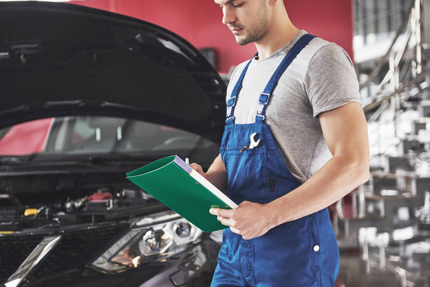 car service, repair, maintenance and people concept - auto mechanic man or smith with clipboard at workshop. - Foto, Imagem