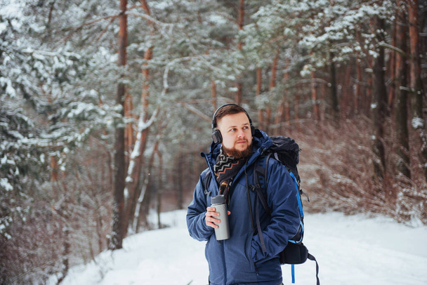 Man Traveler with backpack hiking Travel Lifestyle adventure concept active vacations outdoor. Beautiful landscape with forest of coniferous trees and white snow. - Zdjęcie, obraz