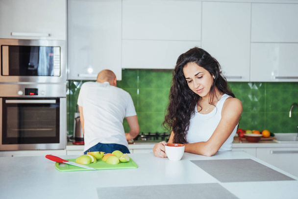 Happy young couple having coffee in the kitchen at home - Photo, image