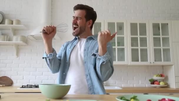 Happy young man holding beater singing dancing cooking in kitchen - Felvétel, videó