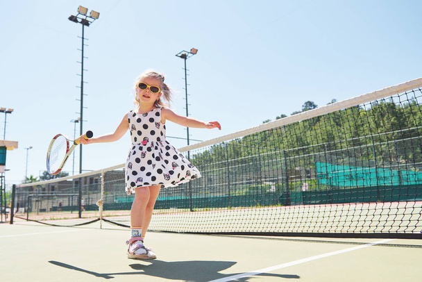 cute little girl playing tennis on the tennis court outside. - Valokuva, kuva