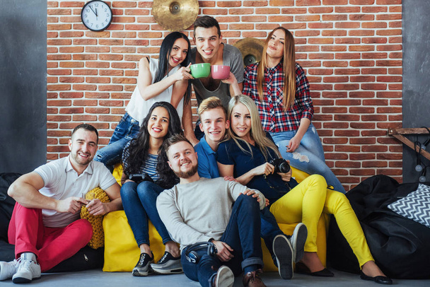 Group portrait of multi-ethnic boys and girls with colorful fashionable clothes holding friend and posing on a brick wall, Urban style people having fun, Concepts about youth and togetherness lifestyle. - Foto, Bild