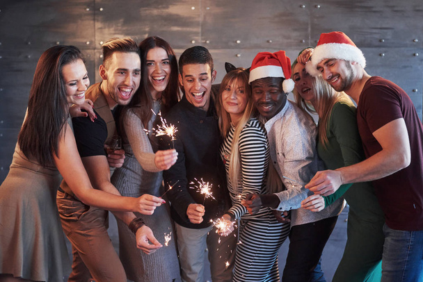 Party with friends. Group of cheerful young people carrying sparklers and champagne flutes. Concepts about youth togetherness lifestyle. - Foto, Imagem