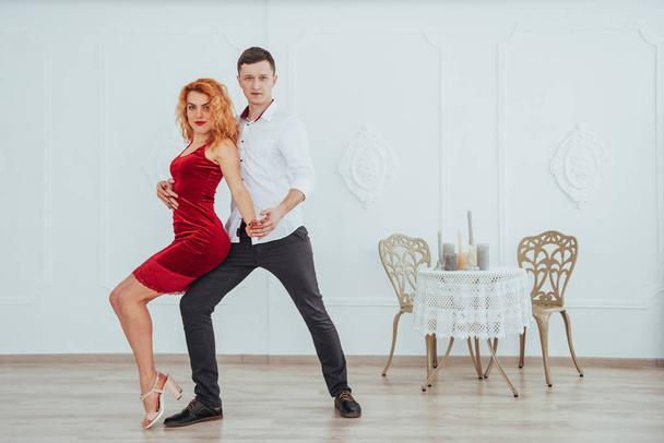 Young beautiful woman in a red dress and a man dancing, isolated on a white background in the studio - Fotoğraf, Görsel