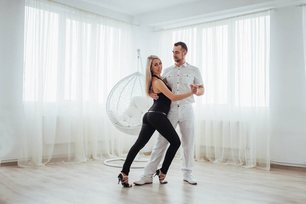 Young couple dancing latin music: Bachata, merengue, salsa. Two elegance pose on white room. - Foto, immagini