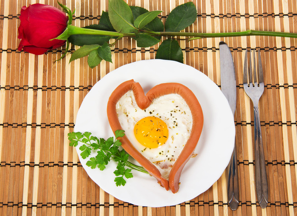 Festive a breakfast on Valentine's Day, sausage in the form of heart, red rose on a bamboo napkin - Fotografie, Obrázek