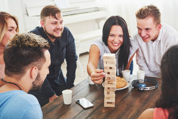 Group of creative friends sitting at wooden table. People having fun while playing board game. - Foto, Imagen