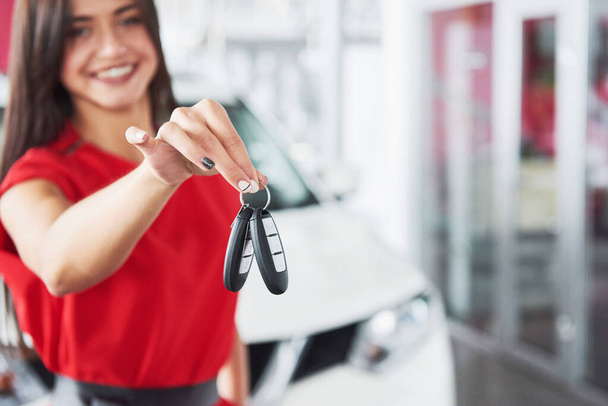 Smiling car salesman handing over your new car keys, dealership and sales concept. Happy girl the buyer. - Photo, image