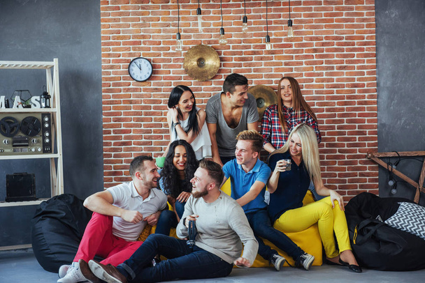 Group portrait of multi-ethnic boys and girls with colorful fashionable clothes holding friend and posing on a brick wall, Urban style people having fun, Concepts about youth and togetherness lifestyle. - Foto, Bild