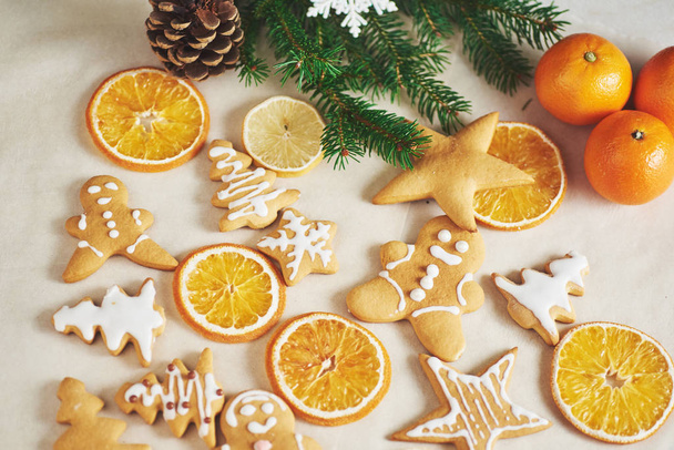 Christmas gingerbread cookies and dried orange and spices on white table. Chairs Christmas trees, cones and Christmas decorations. - Фото, зображення