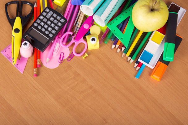 Set mit hellen Bürogeräten, Schulheften und Apfel auf dem Tisch - Foto, Bild