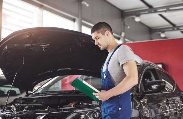 car service, repair, maintenance and people concept - auto mechanic man or smith with clipboard at workshop. - Φωτογραφία, εικόνα