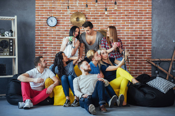 Group portrait of multi-ethnic boys and girls with colorful fashionable clothes holding friend and posing on a brick wall, Urban style people having fun, Concepts about youth and togetherness lifestyle. - Foto, imagen