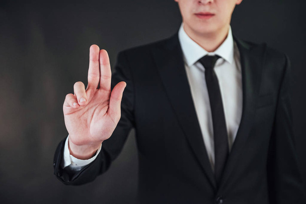 The young businessman in a suit shows his hand on a dark background isolated - 写真・画像