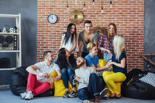 Group portrait of multi-ethnic boys and girls with colorful fashionable clothes holding friend and posing on a brick wall, Urban style people having fun, Concepts about youth and togetherness lifestyle. - Valokuva, kuva