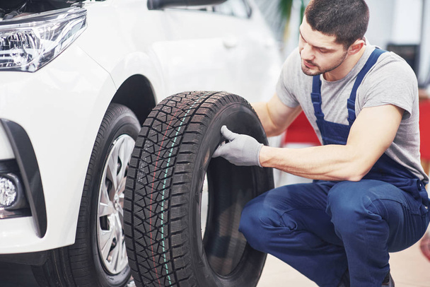 Mechanic holding a tire tire at the repair garage. replacement of winter and summer tires. - Φωτογραφία, εικόνα