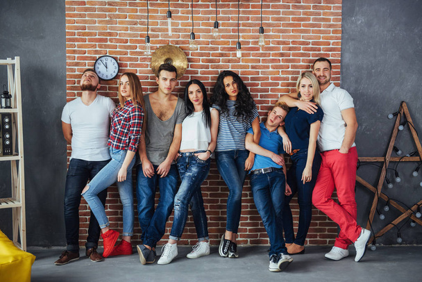 Group portrait of multi-ethnic boys and girls with colorful fashionable clothes holding friend and posing on a brick wall, Urban style people having fun, Concepts about youth and togetherness lifestyle. - Foto, immagini