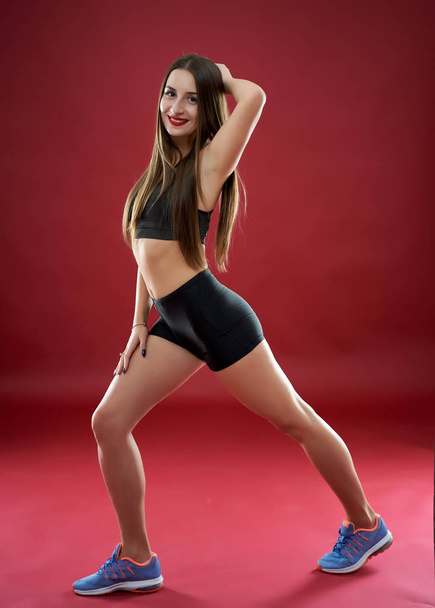 Beautiful young woman doing workout on red background - 写真・画像