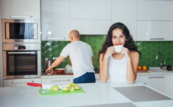 Happy young couple having coffee in the kitchen at home - Zdjęcie, obraz