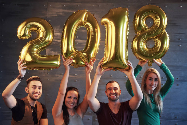 A group of merry young people hold numbers indicating the arrival of a new 2018 year. The party is dedicated to the celebration of the new year. Concepts about youth togetherness lifestyle. - Foto, Bild