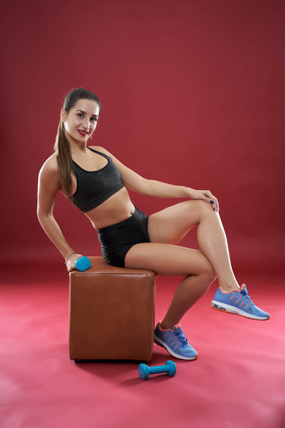 Beautiful young woman doing workout on red background - Foto, immagini