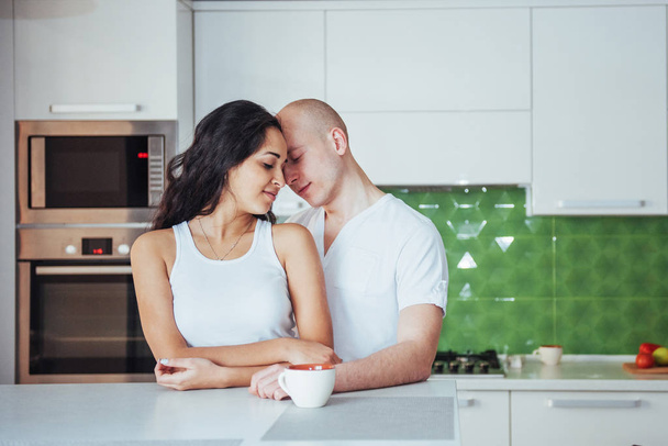 Happy young couple having coffee in the kitchen at home - Fotoğraf, Görsel