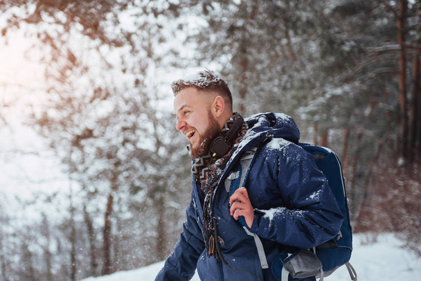 Man Traveler with backpack hiking Travel Lifestyle adventure concept active vacations outdoor. Beautiful landscape with forest of coniferous trees and white snow. - Фото, зображення