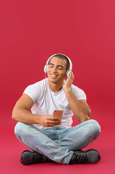 Portrait of handsome young man listening to music on color background - Fotó, kép