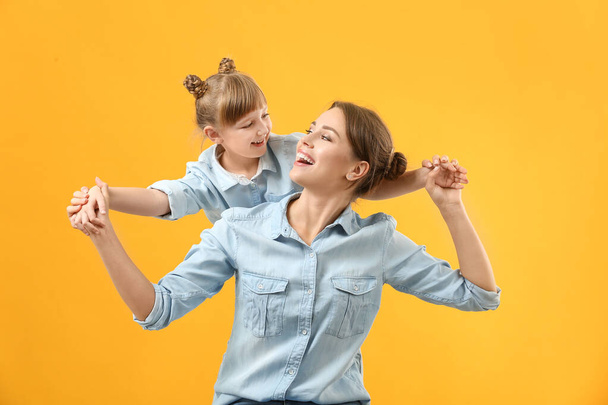 Portret van gelukkige moeder en dochter op kleur achtergrond - Foto, afbeelding