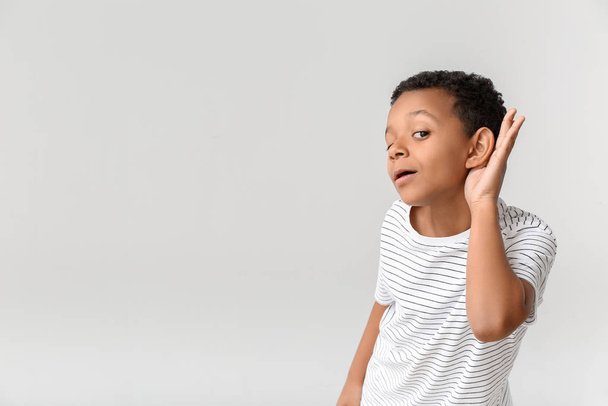 Kleine Afro-Amerikaanse jongen met gehoorprobleem op lichte achtergrond - Foto, afbeelding