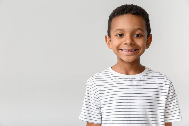 Kis afro-amerikai fiú hallókészülékkel, könnyű háttérrel - Fotó, kép
