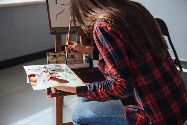 Pretty Pretty Girl artist paints on canvas painting on the easel. Model in the studio - 写真・画像
