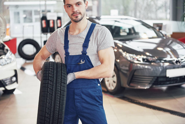Mechanic holding a tire tire at the repair garage. replacement of winter and summer tires. - Foto, Imagem