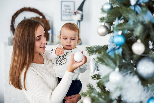 feliz familia madre y bebé decorar árbol de Navidad
. - Foto, Imagen
