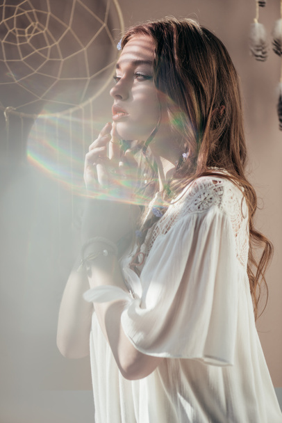 κομψό κορίτσι με πλεξούδες σε hairstyle ποζάρουν σε λευκό φόρεμα boho σε γκρι με φωτοβολίδες  - Φωτογραφία, εικόνα