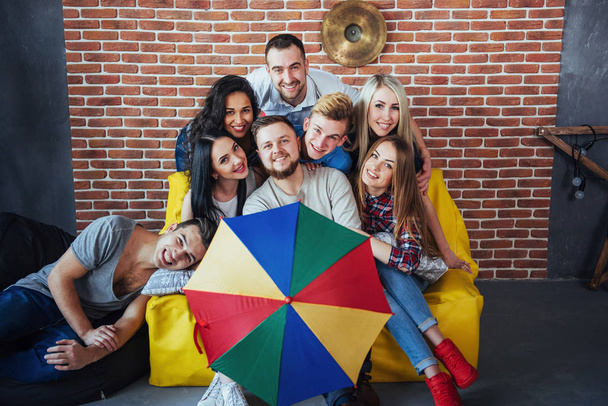 Group portrait of multi-ethnic boys and girls with colorful fashionable clothes holding friend and posing on a brick wall, Urban style people having fun, Concepts about youth and togetherness lifestyle. - Фото, зображення