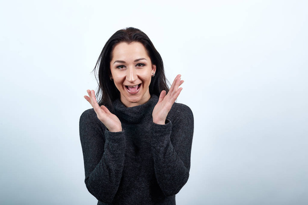Cheerful woman in fashion black sweater spreads hands, smiling, looking happy - Photo, image