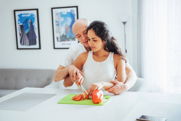 Beautiful young couple grinds vegetables together in the kitchen - Photo, Image