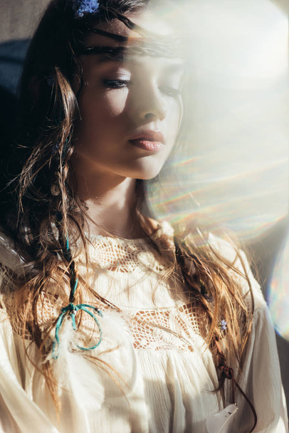 beautiful girl with braids in hairstyle posing in white boho dress on grey with lens flares  - Photo, Image