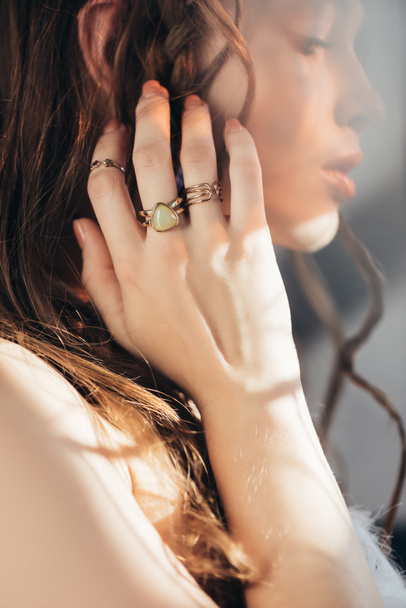 boho menina com tranças no penteado e anéis na mão posando em cinza com flares de lente
  - Foto, Imagem