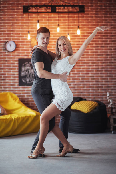 Young couple dancing latin music: Bachata, merengue, salsa. Two elegance pose on cafe with brick walls. - Fotoğraf, Görsel