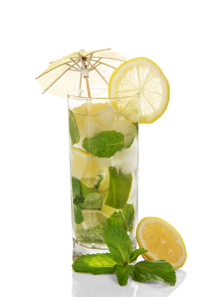 The glass of a cold mojito is decorated with an umbrella, slices of a lemon and mint - Zdjęcie, obraz
