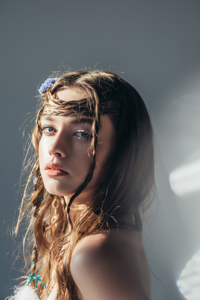 young naked boho girl with braids in hairstyle posing on grey with lens flares  - Photo, Image