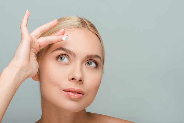 attractive woman applying face cream isolated on grey  - Фото, изображение