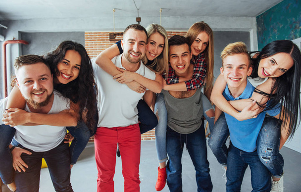 Group portrait of multi-ethnic boys and girls with colorful fashionable clothes holding friend and posing on a brick wall, Urban style people having fun, Concepts about youth and togetherness lifestyle. - Foto, afbeelding