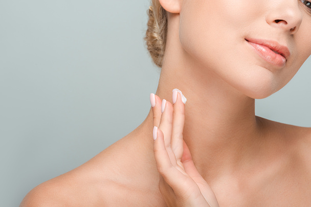 обрізаний вид жінки, що наносить косметичний крем на шию ізольовано на сірий
  - Фото, зображення