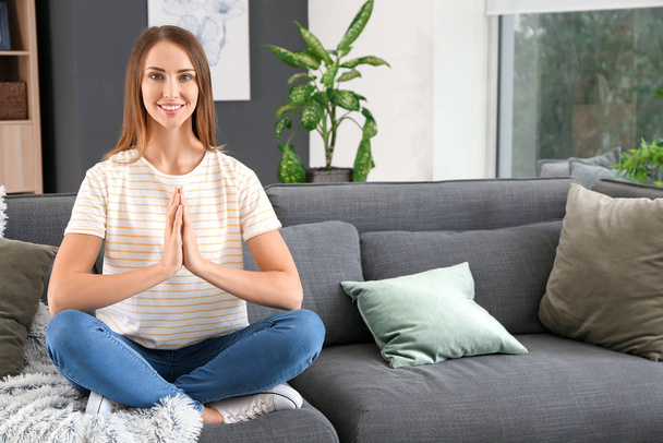Красивая молодая женщина медитирует дома
 - Фото, изображение
