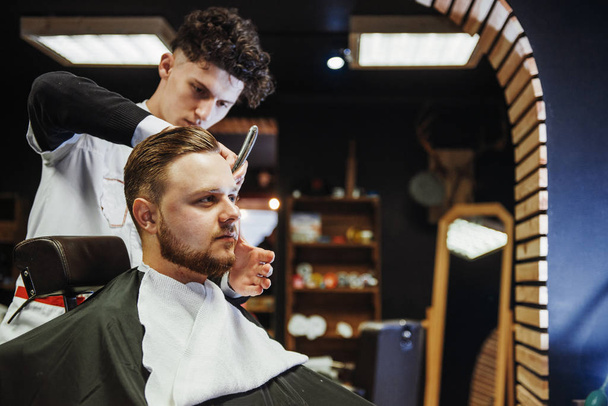 Men's hairstyling and haircutting in a barber shop or hair salon. Men's Hairdressers barbers. - Фото, изображение