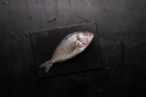 вид свежей рыбы на черной доске
 - Фото, изображение