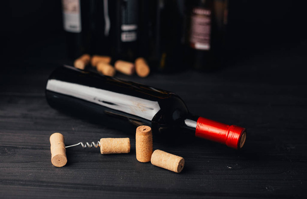 close-up view of wine bottles with corks and corkscrew on wooden surface - Photo, image